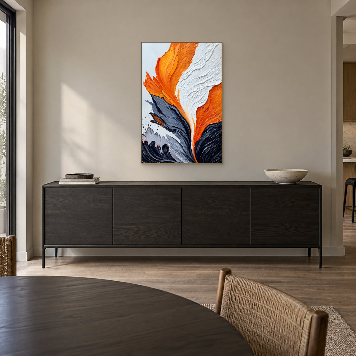 Orange and white textured painting in a champagne-tone frame above a dark sideboard in a dining room