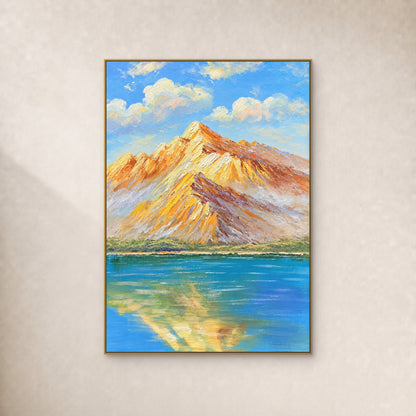 Amber mountain ridges and their blue-lake reflection in a thin gold-tone floating frame on an ivory wall