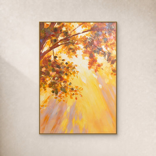 Vertical painting of amber autumn leaves and golden light in a slim gold floating frame on an ivory wall.