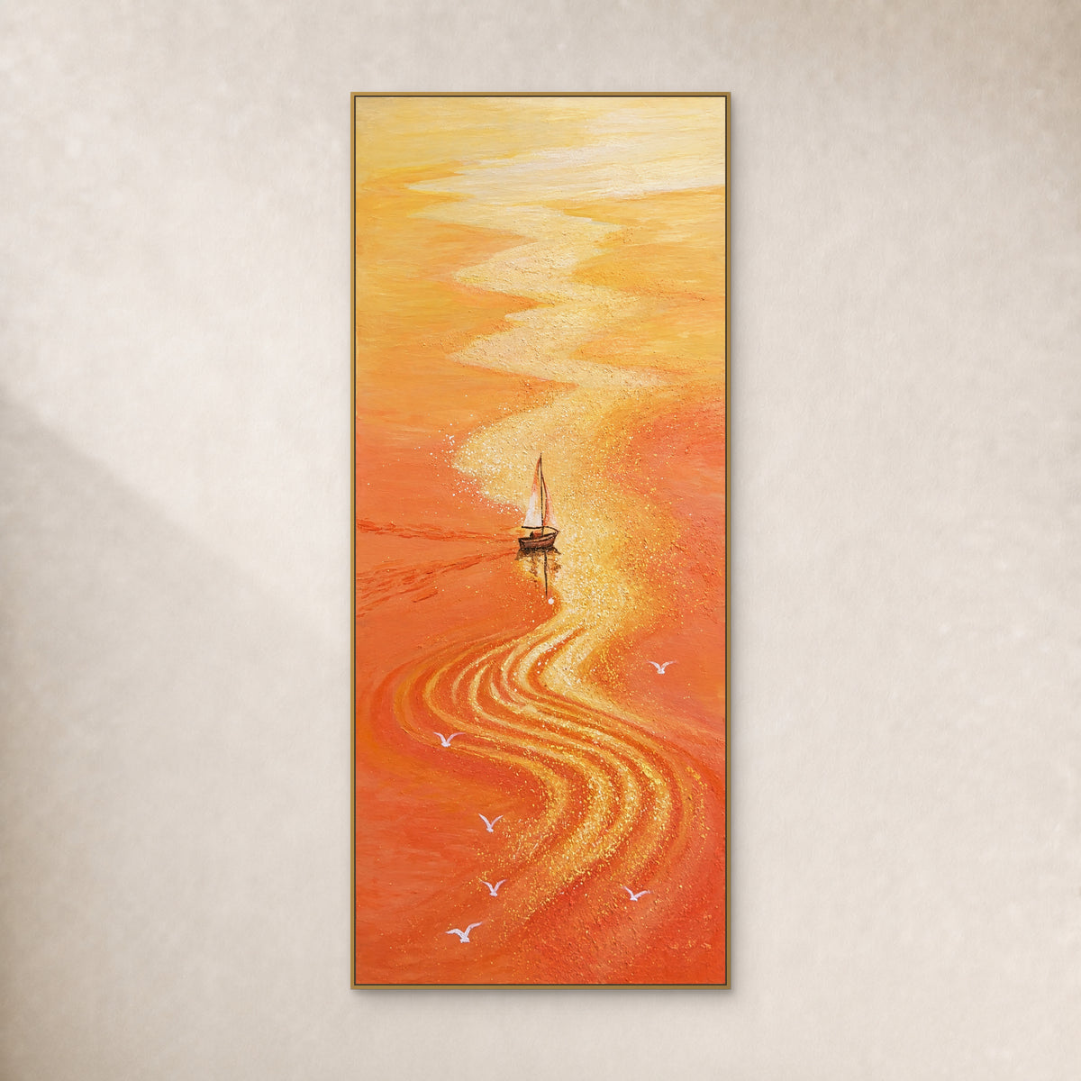 Tall orange seascape with a white sailboat and a winding gold reflection, in a thin gold-tone frame on an ivory wall