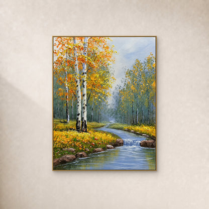 Golden autumn birches and a blue woodland stream with a small cascade, in a slim gold frame on an ivory wall.