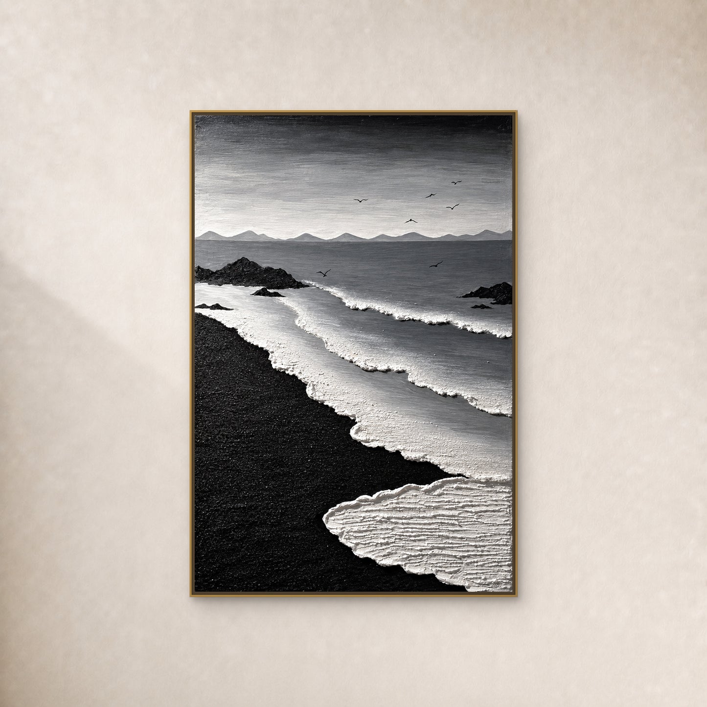 Black and white coastal painting with curving surf, black sand and seven birds, in a thin gold-tone floating frame on a warm ivory wall