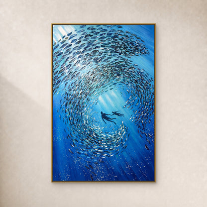 Blue fish spiral around two divers in a thin gold-toned floating frame on a continuous ivory wall