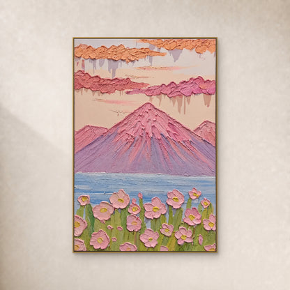 Pink and lilac mountain above a blue lake and raised flowers, shown in a thin gold frame on an ivory wall