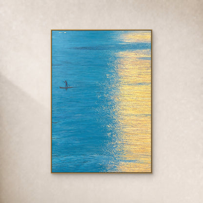 Turquoise water and a small boat beside golden reflections, in a slim gold floating frame on an ivory wall