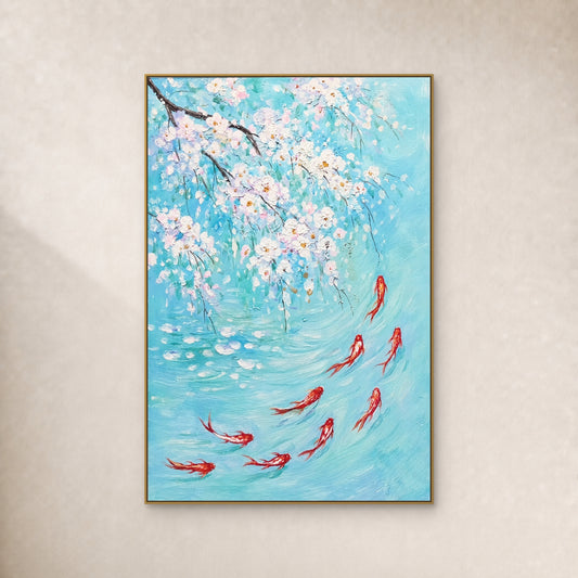 Nine red-and-white koi beneath white blossoms in turquoise water, in a slim gold-coloured floating frame on an ivory wall.