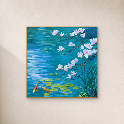 Square painting of pink magnolia branches over blue water with two koi, in a slim gold-tone frame on an ivory wall