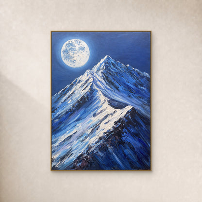 Pale full moon above blue snow peaks in a thin gold-tone floating frame on an ivory wall