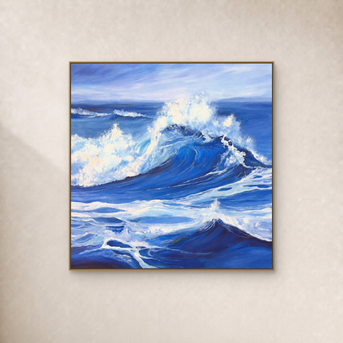 Periwinkle-blue breaking wave and white sea foam in a thin gold frame on an ivory wall