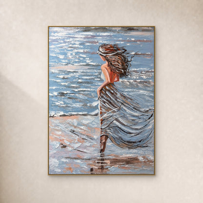 Woman with windblown hair and a blue-grey dress beside the sea, in a thin gold-toned floating frame on an ivory wall