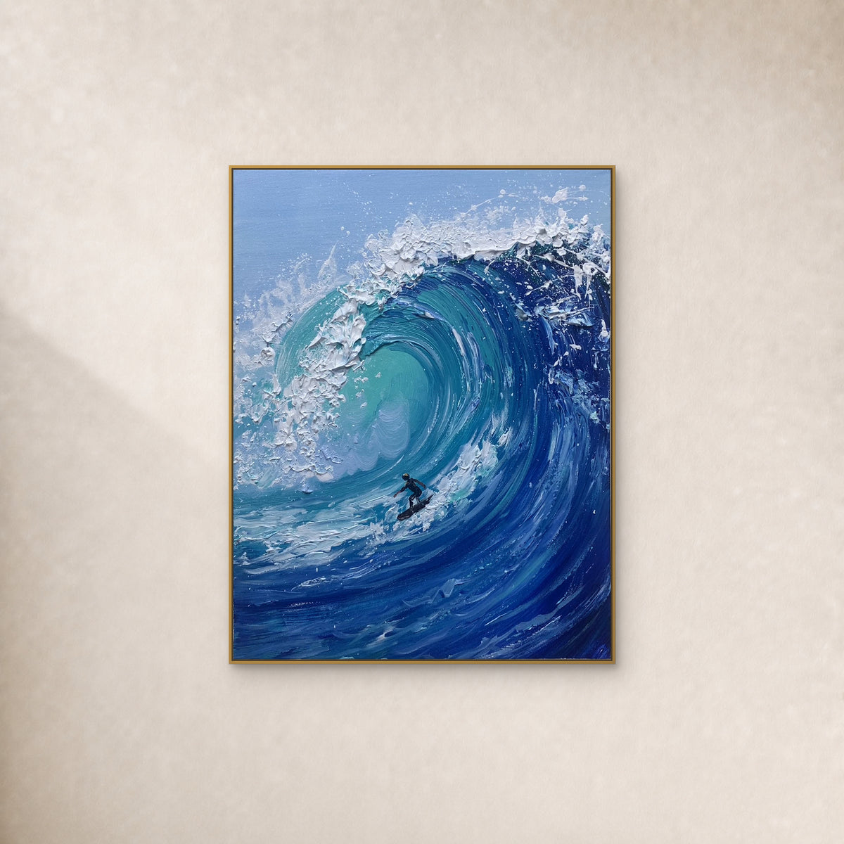 Small surfer inside a turquoise wave with raised white foam, in a slim gold-tone frame on an ivory wall