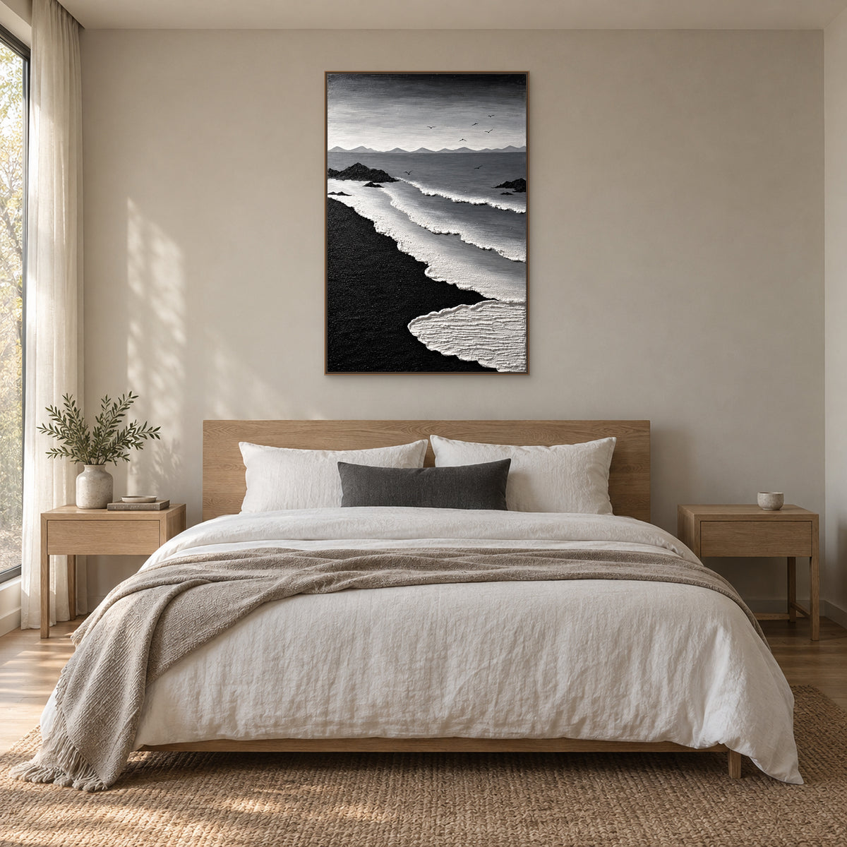 Black and white surf painting in a wood-tone floating frame centred above an oak-tone bed with ivory linen and a charcoal cushion