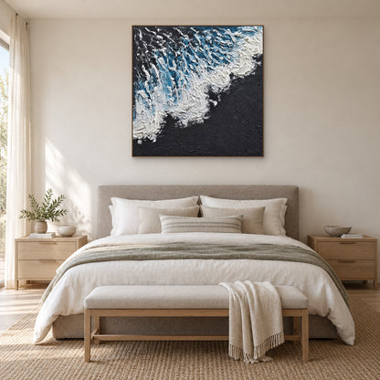 Blue and white surf on a charcoal ground in an oak-tone frame above a grey upholstered bed