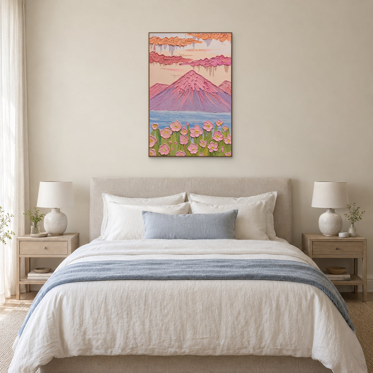 Pastel mountain and flower painting in an oak-tone frame centred above an upholstered bed