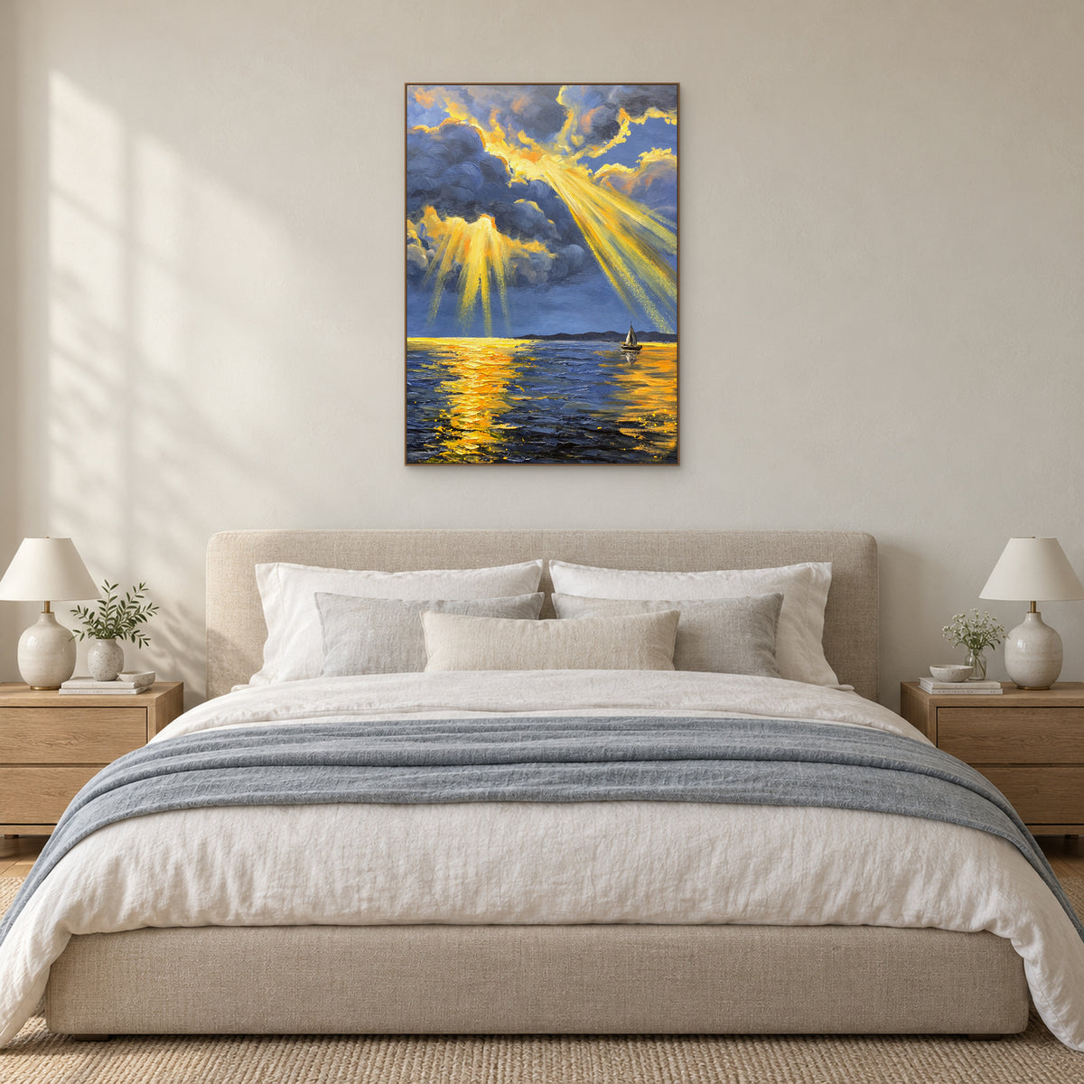 Golden sunbeam seascape in an oak-tone floating frame above an upholstered bed with blue-grey bedding.