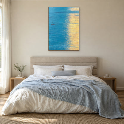 Blue and gold water painting in an oak-tone frame centred above a linen bed