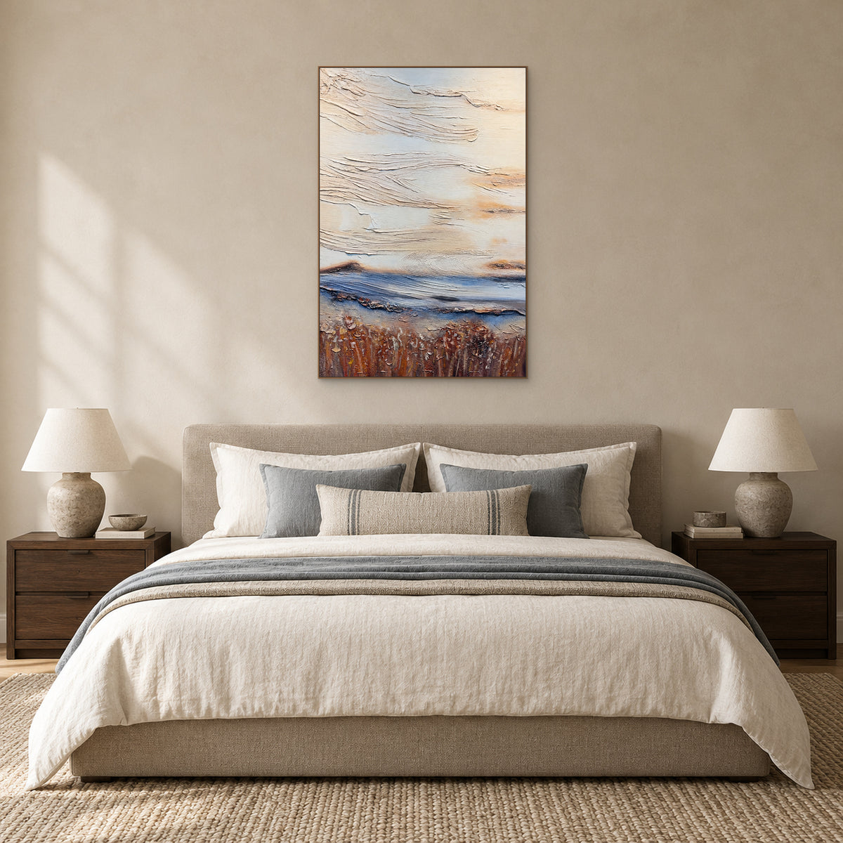 Ivory, blue and ochre abstract in an oak-coloured frame centred above a beige upholstered bed with blue-grey cushions