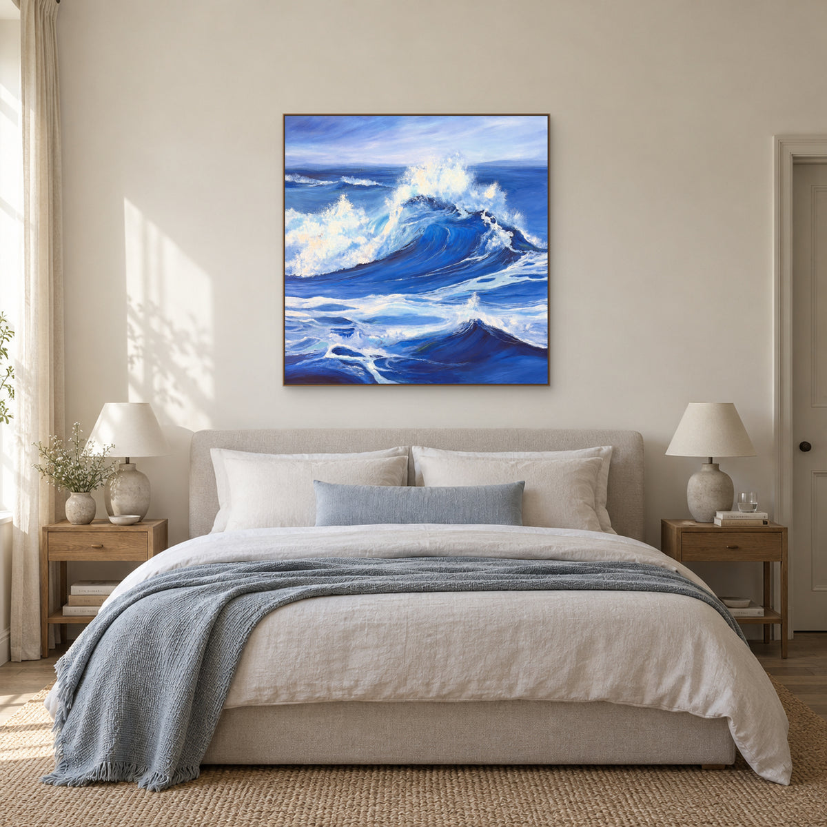 Blue and white wave painting in an oak-toned frame above a linen bed with a blue throw