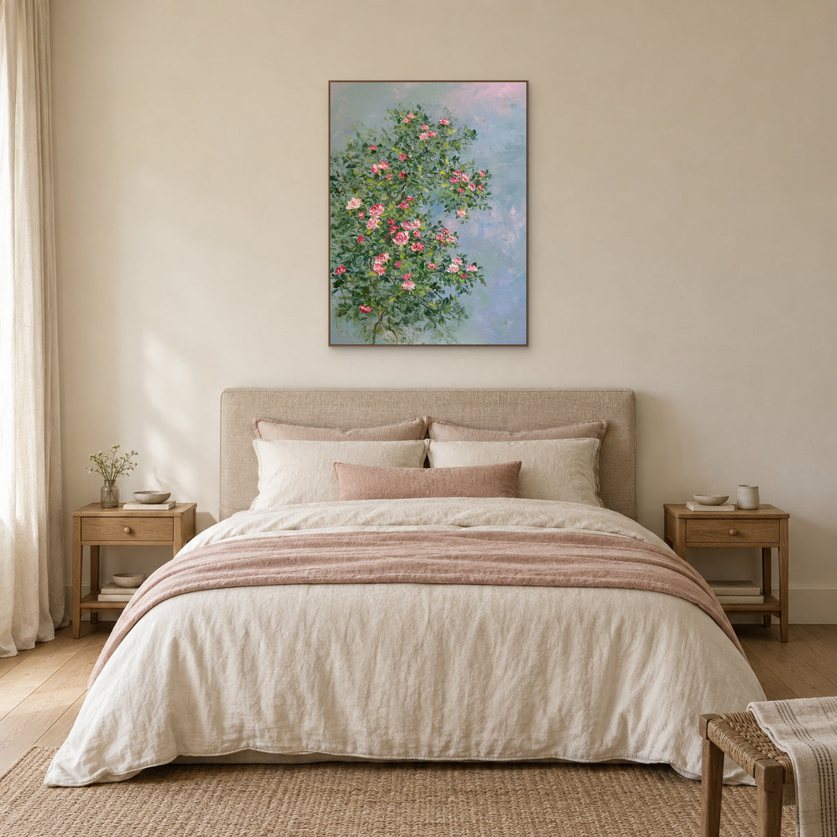 Pink rose painting in a thin oak-tone frame centred above an upholstered headboard in a warm neutral bedroom