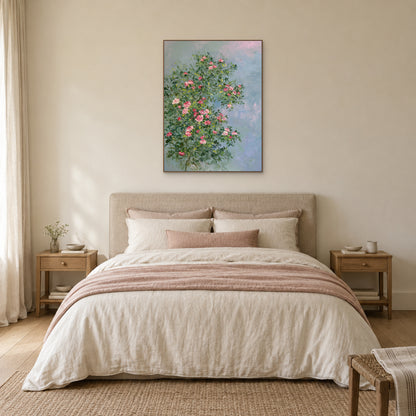 Pink rose painting in a thin oak-tone frame centred above an upholstered headboard in a warm neutral bedroom