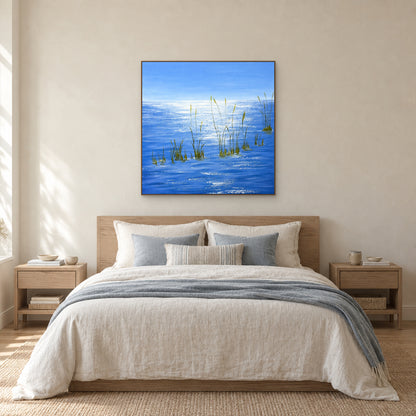 Blue water painting in an oak-tone floating frame centred above a pale linen bed