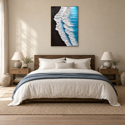 White surf painting in an oak-tone frame centred above a wooden headboard and cream bedding