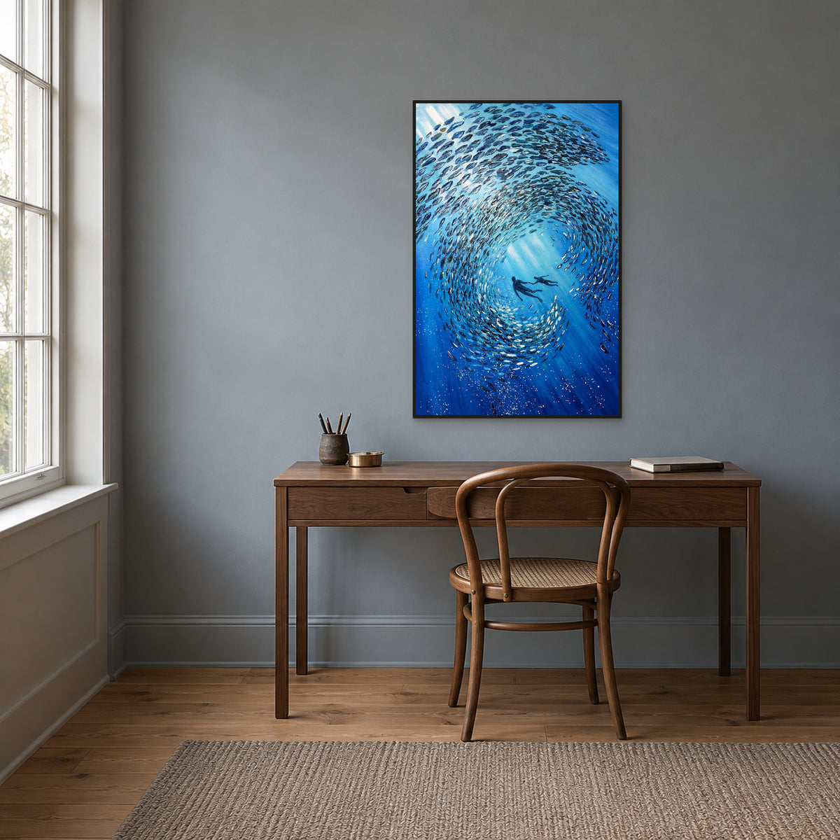 Fish school and two divers in a black floating frame above a walnut-toned desk against a blue-grey wall