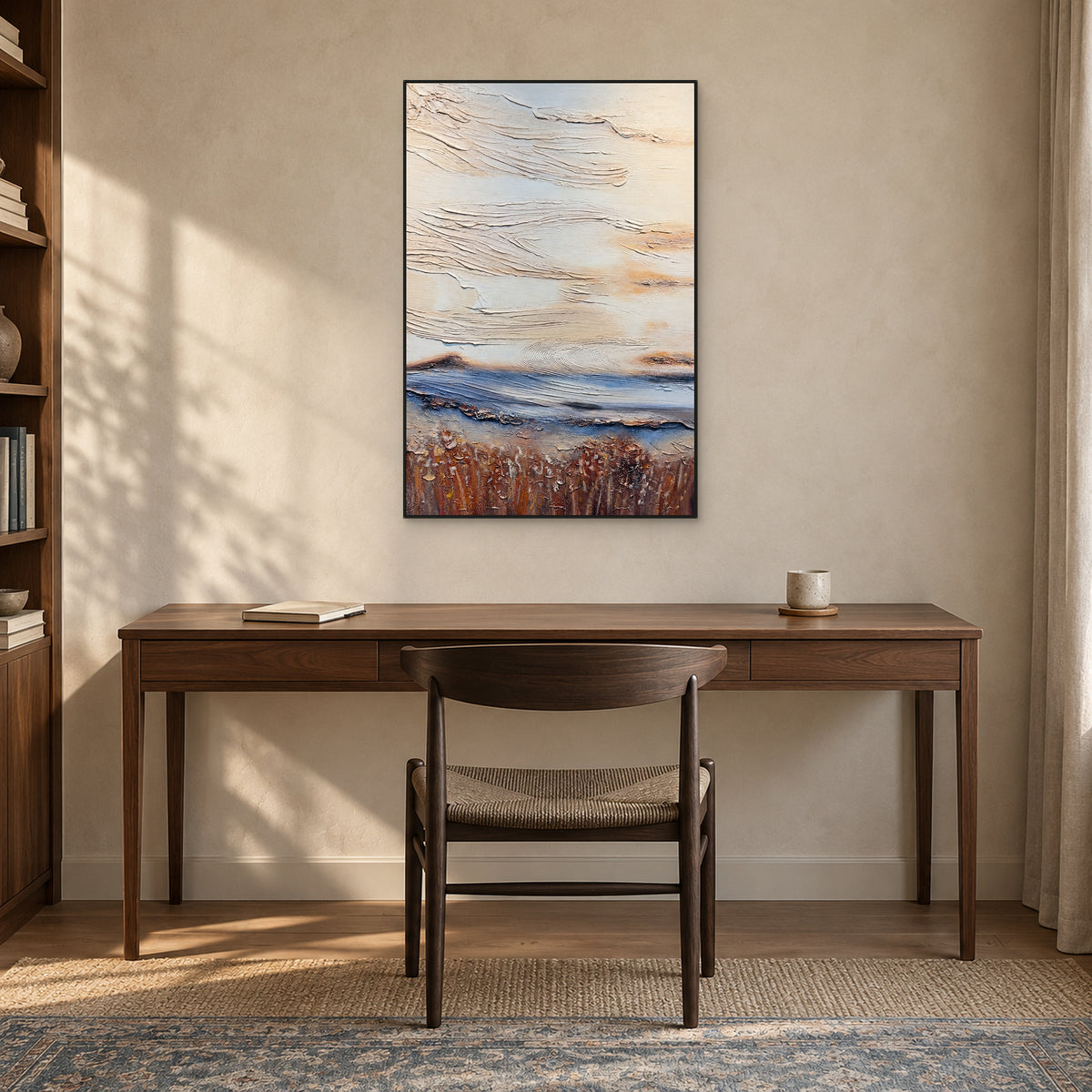 Tall textured abstract in a thin black frame above a dark wooden desk and woven-seat chair