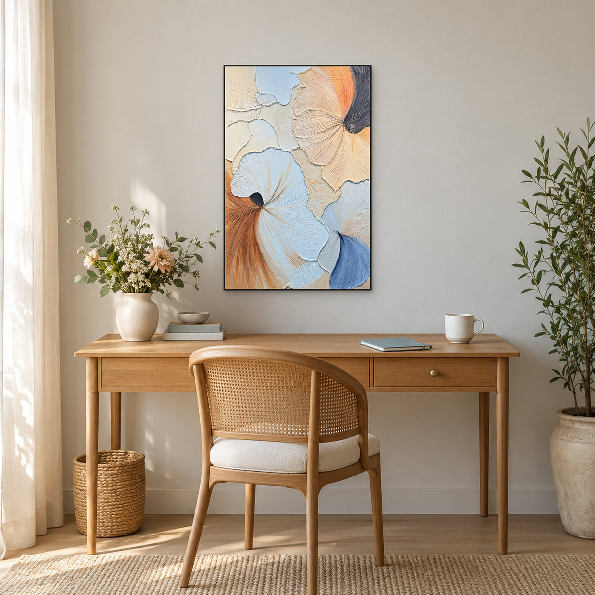Pastel relief painting in a thin black frame above an oak desk and cane-backed chair, with flowers to the left