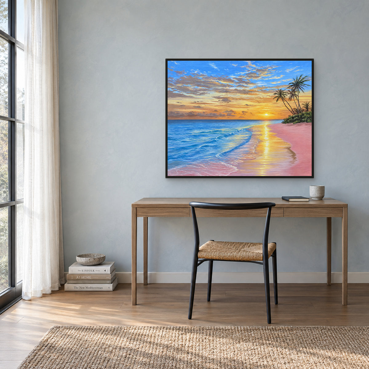 Sunset beach painting in a black floating frame above a light wood desk against a blue-grey wall