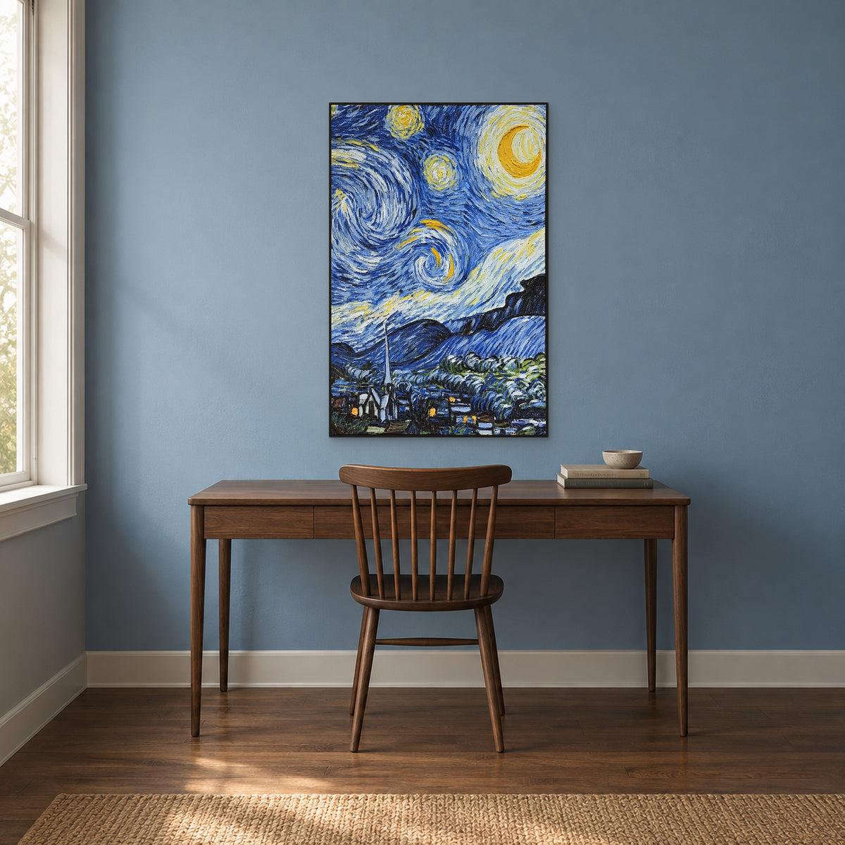 Crescent moon and swirling blue sky in a black frame above a walnut desk against a muted blue study wall.