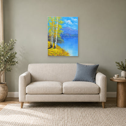White-framed birch lake landscape above a small cream sofa, with a blue cushion and plants.