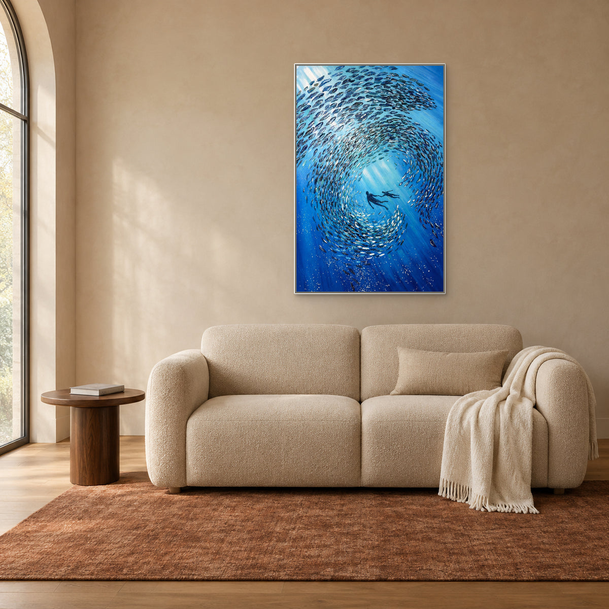 Vertical blue fish painting in a white floating frame above a biscuit-coloured settee beside an arched window