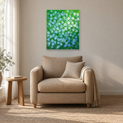 Blue and white flax flower painting in a white floating frame beside a quiet reading chair