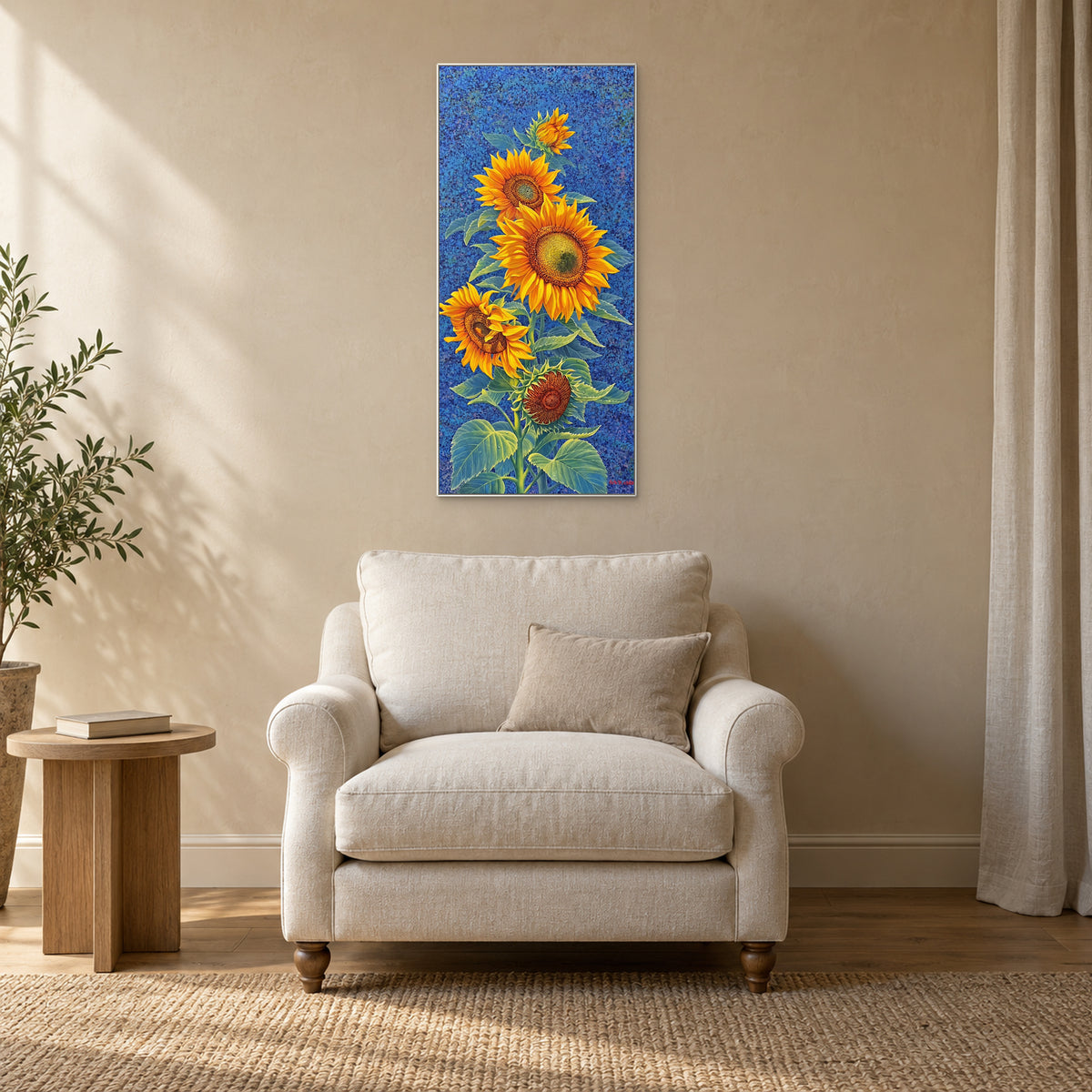 White-framed sunflower painting above a cream reading chair beside a small wooden table