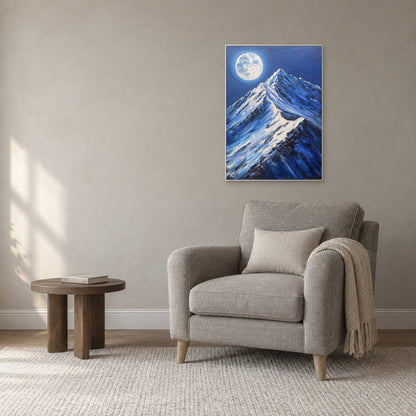 Blue nocturnal mountain artwork in a white frame above a grey reading armchair