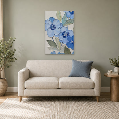White-framed blue floral painting above a cream loveseat beside a leafy plant in a reading corner