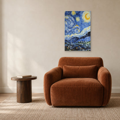 Blue and yellow night sky painting in a white frame above a rust-coloured reading chair beside a small wooden table.