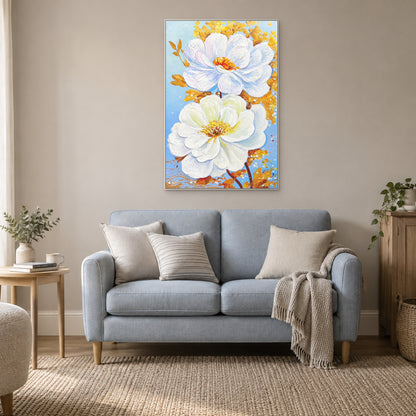 Two white blossoms in a white floating frame above a blue reading sofa with cream cushions.