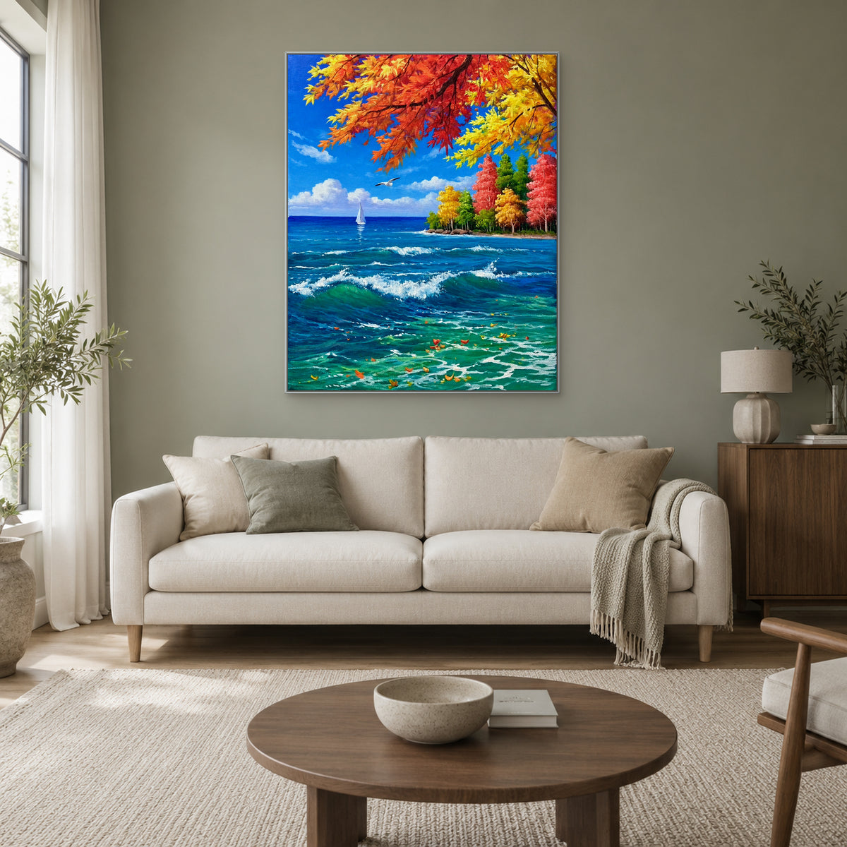 Colourful autumn leaves and breaking waves in a silver-tone frame above a cream sofa on a sage wall