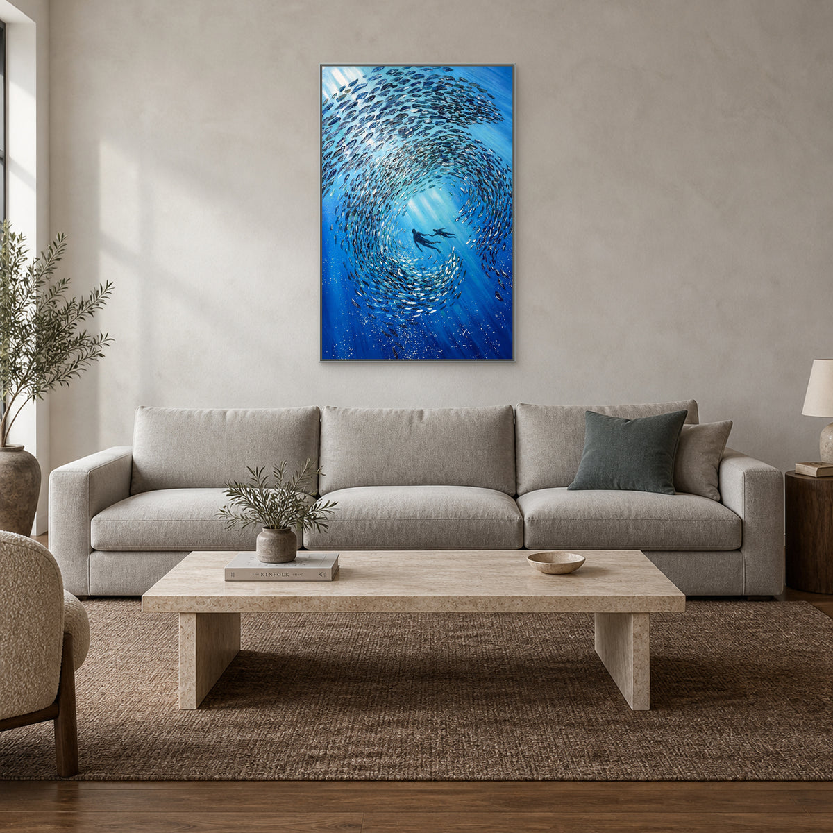 Blue fish school painting in a silver-toned floating frame above a pearl-grey sofa and pale stone coffee table