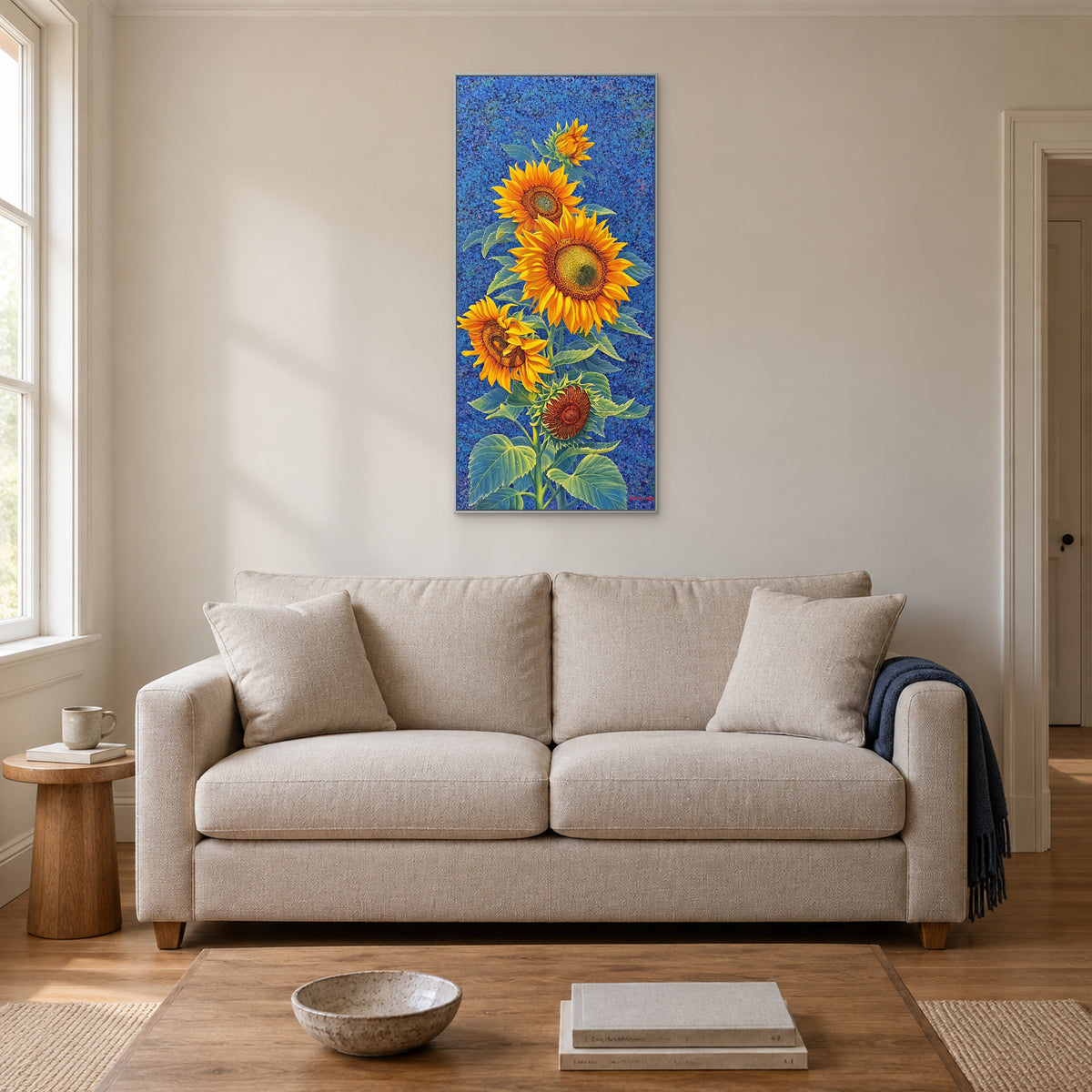 Tall cobalt-blue sunflower artwork in a silver-tone frame centred above a pale upholstered sofa