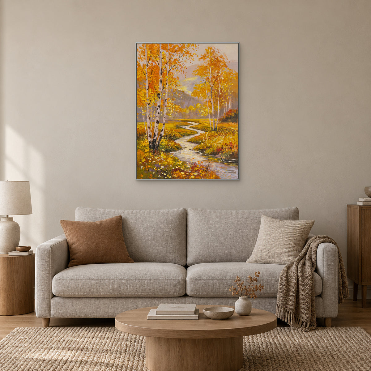 Vertical autumn landscape in a silver-toned frame centred above an ivory sofa