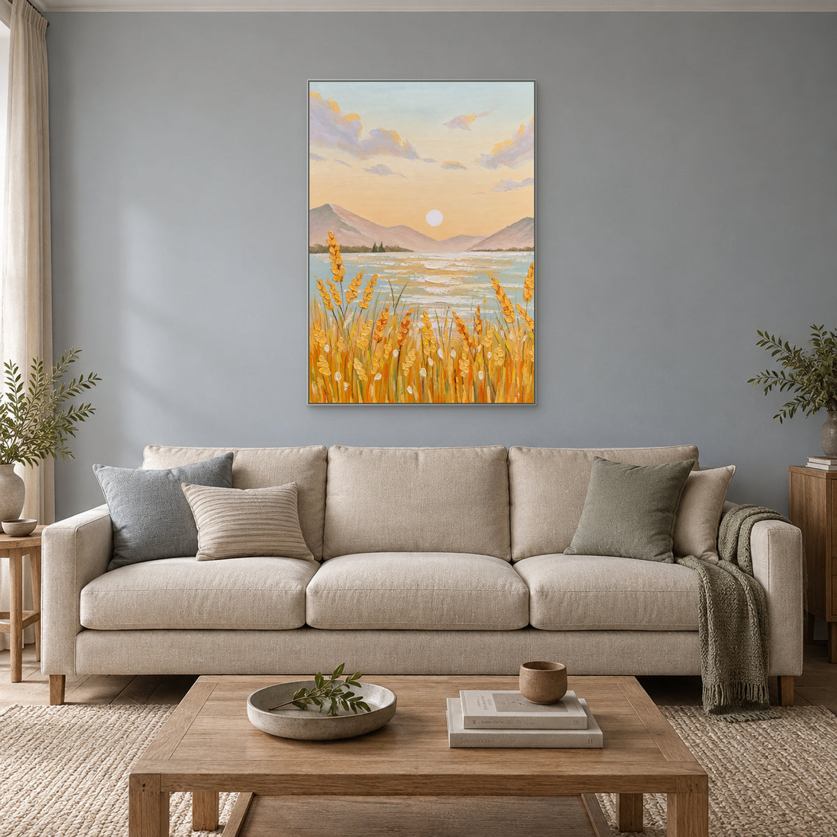 Vertical harvest landscape in a silver-tone frame above a cream sofa on a blue-grey wall