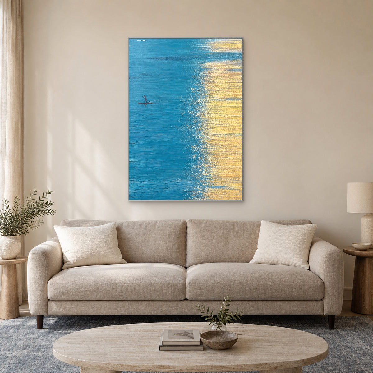 Turquoise water and gold reflection painting in a silver-tone frame above a light taupe sofa