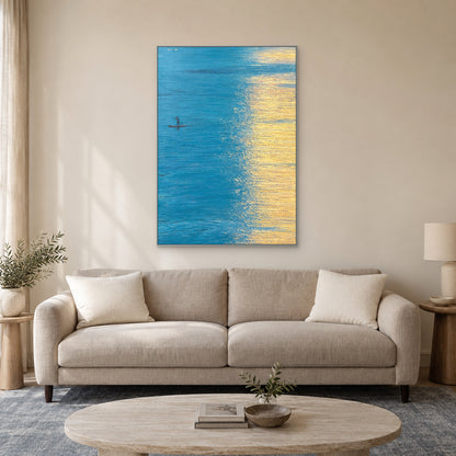Turquoise water and gold reflection painting in a silver-tone frame above a light taupe sofa