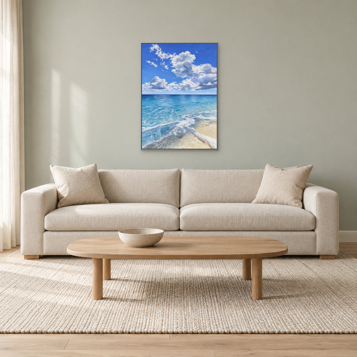 Blue ocean painting in a silver-tone floating frame above an oatmeal sofa on a pale sage-grey wall