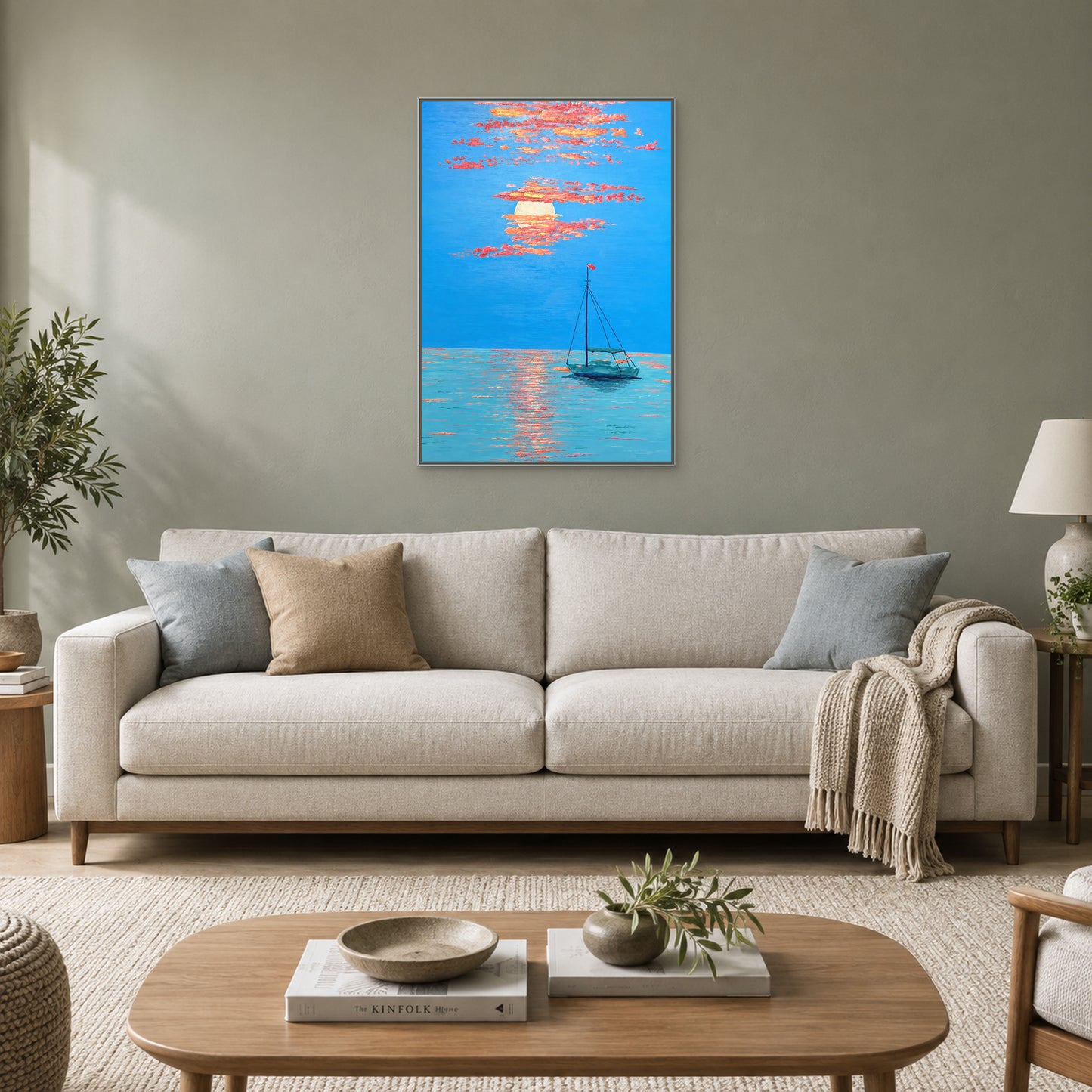 Solitary boat and coral clouds in a silver-tone floating frame above an oatmeal sofa against a muted sage-grey wall.
