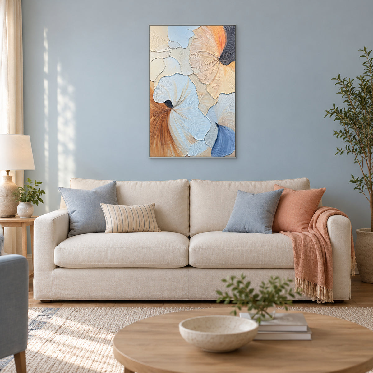 Pastel fan-shaped abstract in a silver-coloured frame on a blue-grey wall above an ivory sofa with blue and peach accents