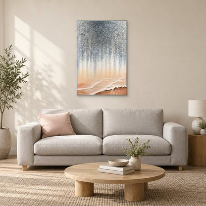 Tall grey and peach abstract in a silver-toned frame above a cream sofa with a blush cushion and round wooden table